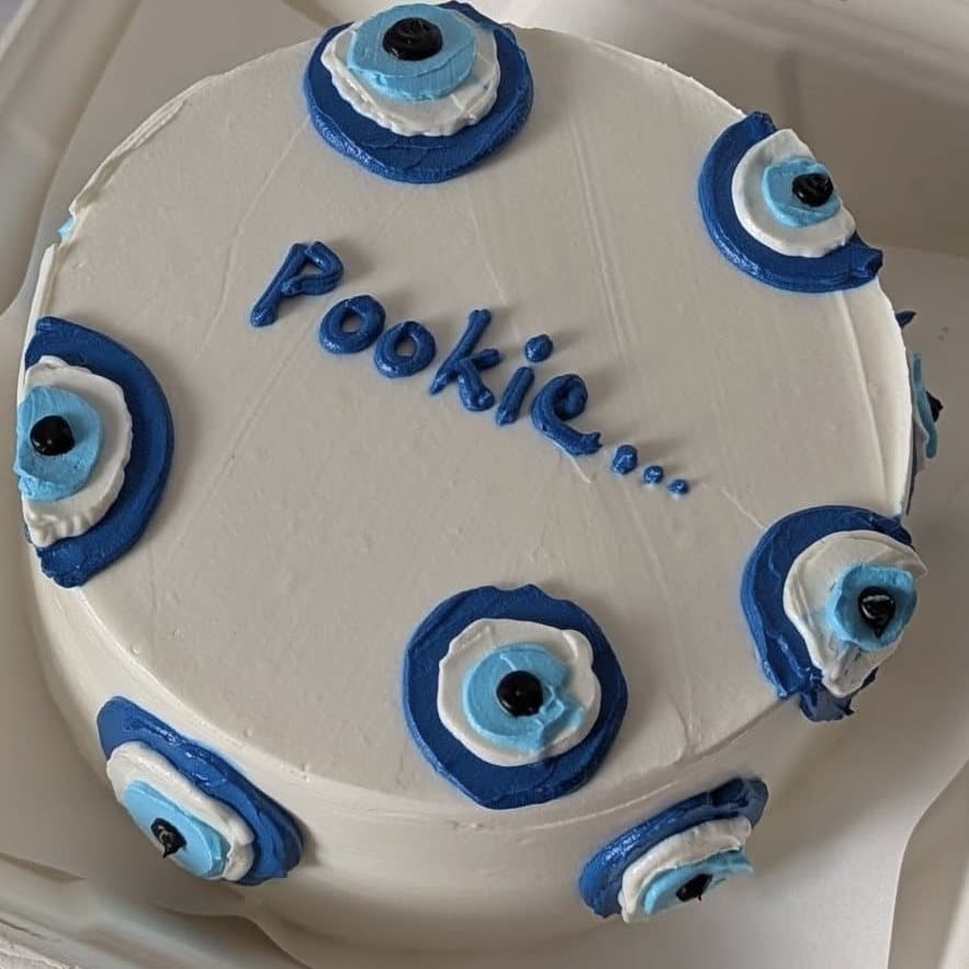 Cream cake with blue nazar evil eye piping reading Pookie