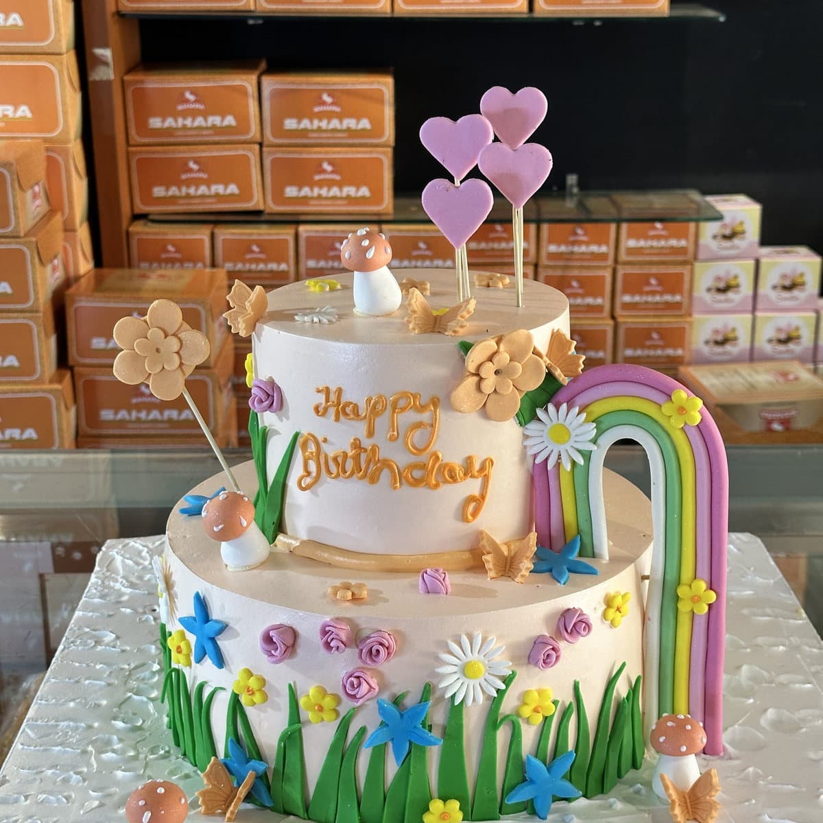 Two-tier rainbow and flower garden birthday cake with pastel hearts, custom made in Rewari