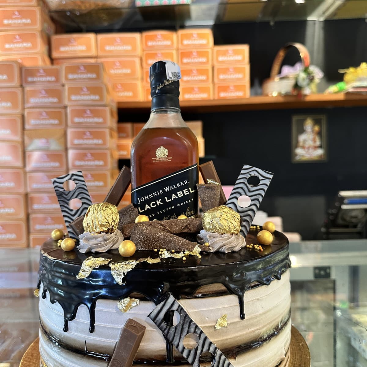 Designer chocolate drip cake with a whisky bottle, Ferrero Rocher and chocolate bars